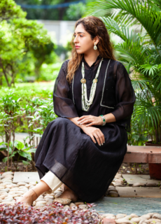 Woman in black embroidered kurta seated in a garden – ethnic wear shoot