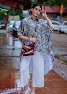 Woman in printed shirt and white trousers with red handbag – street style shoot