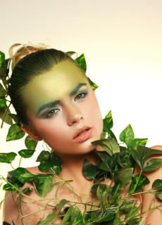 Model with green leaf makeup and foliage – conceptual beauty shoot