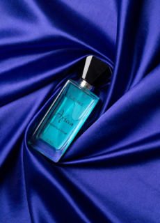 Blue perfume bottle on purple satin – product photography